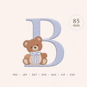May include: An embroidery design featuring a light blue letter B with a textured finish. A brown teddy bear with a light blue bow sits in front of the letter. The design includes the text 85 mm and file formats PES, JEF, DST, EXP, HUS, VIP, XXX.