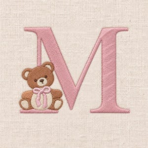 Peut inclure: Une lettre capitale M brodée en fil rose tendre, accompagnée d'un ours en peluche marron avec un nœud rose clair autour du cou placé à la base de la lettre, le tout cousu sur un tissu texturé de couleur beige clair.