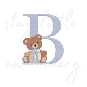 May include: A light blue embroidered letter B with a brown teddy bear wearing a blue bow sitting in front of the letter.