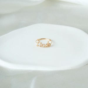Peut inclure: Une bague en or avec le nom "Linda" écrit en fil.