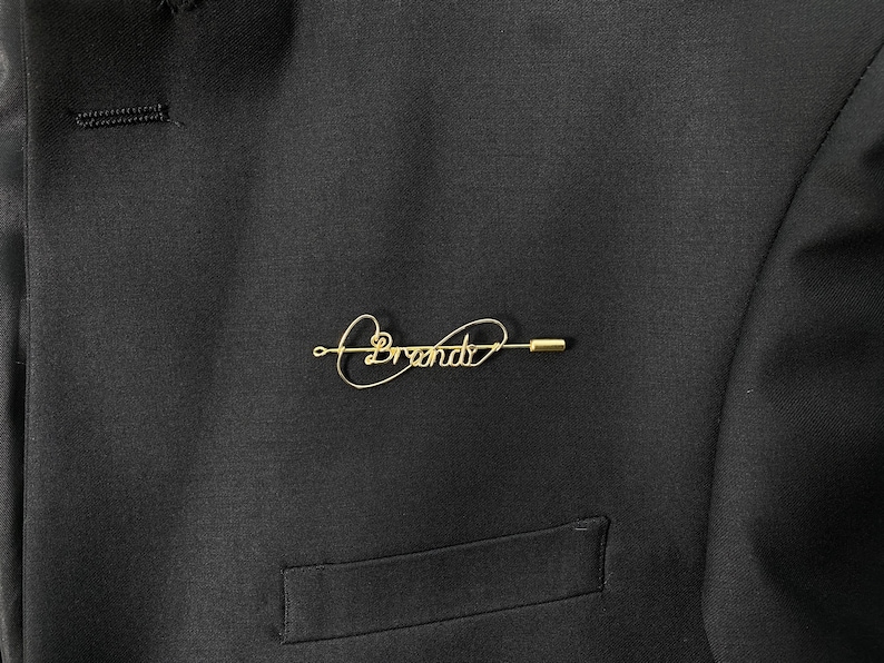 May include: A gold-colored pin with the word "Brenda" written in cursive.