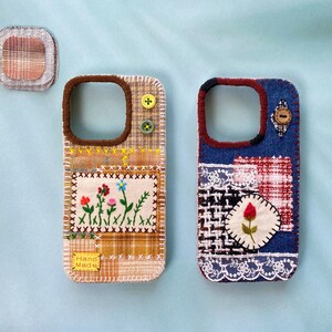 May include: Two handcrafted phone cases with patchwork designs. One case features floral embroidery, the other a red rose. A matching square patch is also present. The cases are adorned with buttons and decorative stitching.
