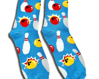 May include: A pair of crew socks with a bright blue background featuring a repeating pattern of white bowling pins, red bowling balls, and yellow bowling balls with starburst accents. The socks have a solid yellow cuff at the top opening.