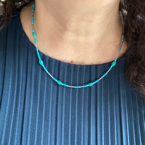 May include: A turquoise and silver beaded necklace with oval-shaped turquoise beads.