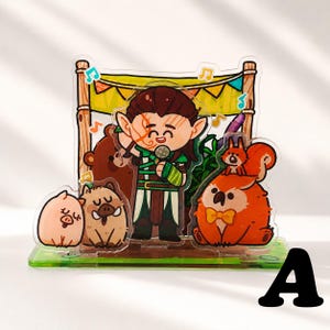 Peut inclure: Un pr&eacute;sentoir en acrylique transparent repr&eacute;sentant un elfe de dessin anim&eacute; chantant dans un microphone sur sc&egrave;ne avec un ours brun, un cochon, un sanglier et une cr&eacute;ature orange avec un &eacute;cureuil sur la t&ecirc;te, orn&eacute; de notes de musique.