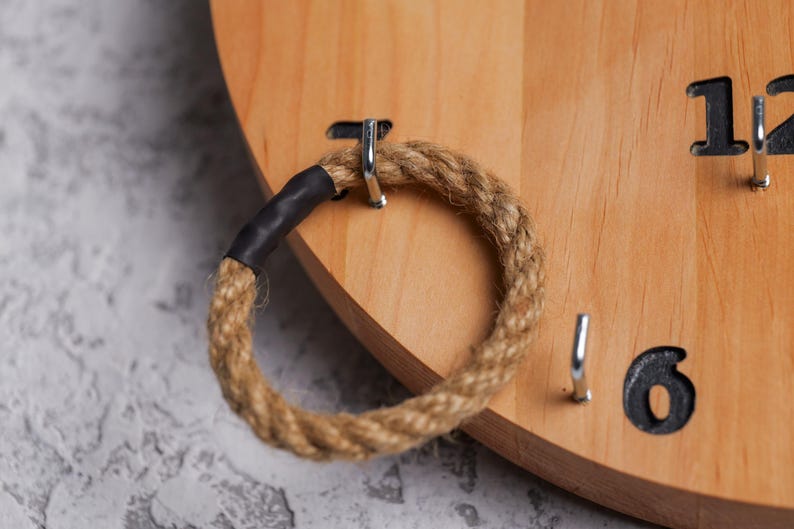 Op de afbeelding: Een houten ringwerpspel met een bruine touwring en metalen haken. De nummers 6 en 12 zijn zichtbaar op het bord.