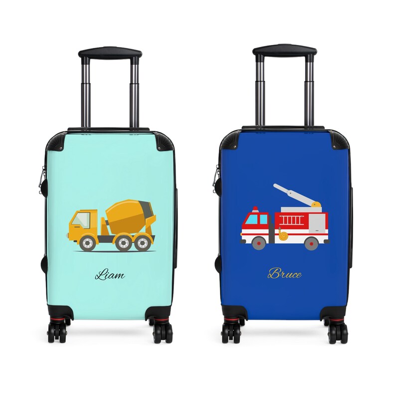 May include: Two blue and turquoise rolling suitcases with wheels. One suitcase has a cement mixer truck design and the name "Liam" printed on it. The other suitcase has a red fire truck design and the name "Bruce" printed on it.