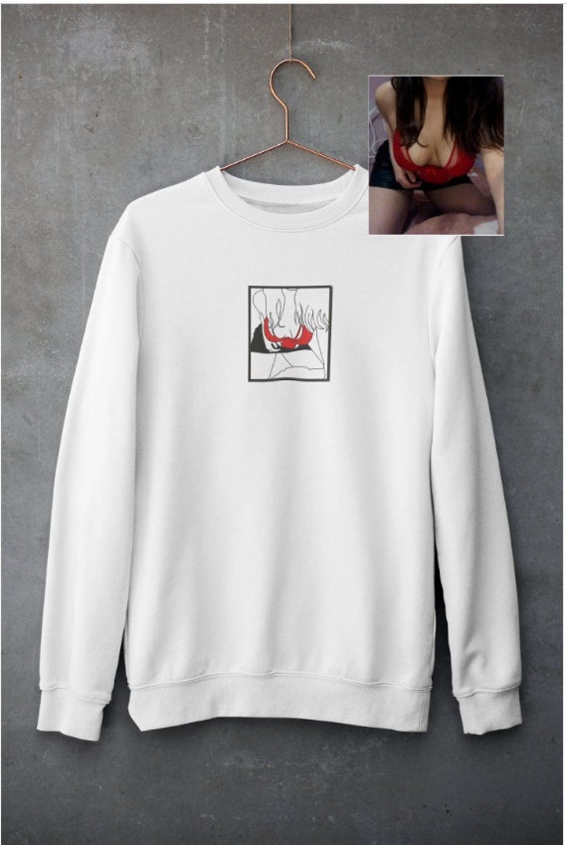 May include: White sweatshirt with a black and red line drawing of a person in a square on the front.