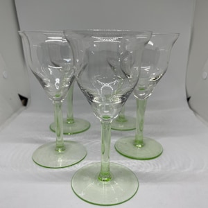 Könnte beinhalten: Satz von fünf klaren Weingläsern mit Stiel aus Glas mit grünem Farbton. Die Gläser haben eine abgerundete Schale und einen zarten Stiel.