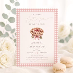 Peut inclure: Une invitation à une baby shower avec une bordure rose à carreaux. L'invitation contient le texte "A Little Cutie Pie is on the Way!" et les détails de la baby shower d'Olivia Richards. Une illustration à l'aquarelle d'une tarte aux cerises est au centre.