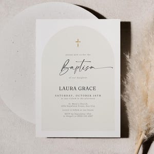 Peut inclure: Une invitation de baptême blanche avec une croix dorée et un motif en arche. Le texte indique "Veuillez vous joindre à nous pour le baptême de notre fille Laura Grace, samedi 16 octobre à 14h00, Église Sainte-Marie, 1234 Anywhere Street, Any City, Déjeuner à suivre à notre domicile, RSVP avant le 25 septembre à Abigail au (555) 123-4567."