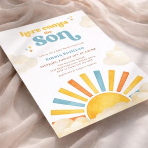May include: Baby shower invitation with the text "Here Comes the Son" in yellow and blue. The invitation features a watercolor sun design with blue, orange, and yellow rays, and fluffy clouds. The invitation is for Emma Sullivan.