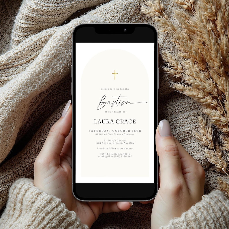 May include: A smartphone displays a baptism invitation. The invitation features a gold cross, the word "Baptism" in elegant script, and details including the daughter's name, date, time, and location. The phone is held against a neutral-toned knitted background.