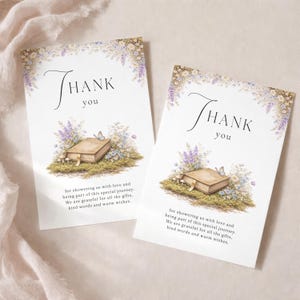 Peut inclure: Deux cartes blanches avec l'inscription "THANK you" en écriture élégante. Chaque carte présente une illustration à l'aquarelle d'un livre, de fleurs et d'un papillon. Le texte en dessous dit "for showering us with love..."