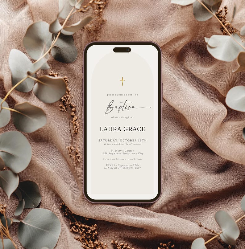 May include: A smartphone displays a baptism invitation with a cross icon and the word "Baptism" in elegant script. The invitation includes the name "LAURA GRACE" and event details. The phone rests on a textured, neutral-toned fabric, adorned with eucalyptus branches.