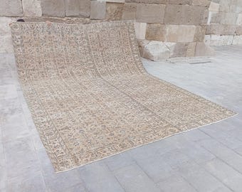 May include: A large rectangular area rug featuring a beige base colour with intricate floral and vine patterns in shades of blue and brown. The rug has a detailed border design and a repeating motif across the central field, displaying a woven texture.