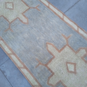 May include: A light blue and beige runner rug with a geometric pattern. The rug has a faded look and is made of a woven material.