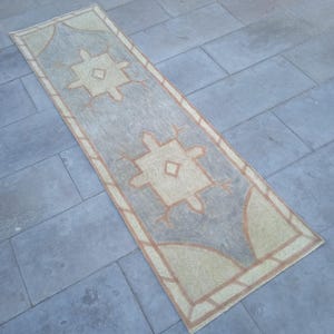May include: A long, rectangular rug with a geometric pattern in shades of beige and brown. The rug has a faded, vintage look and is perfect for adding a touch of bohemian style to any room.