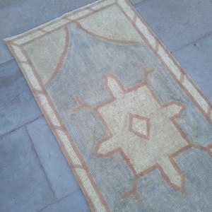 May include: A light blue and beige runner rug with a geometric pattern. The rug has a brown border.