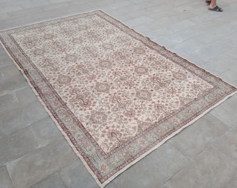 May include: A large, rectangular rug with an intricate floral pattern in cream, pink, and green. The rug has a cream-colored background with a repeating pattern of pink and cream floral motifs. The border is a combination of green and pink.