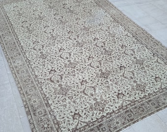 May include: A vintage cream-colored rug with a brown floral pattern. The rug has a decorative border with a paisley design.