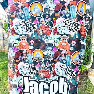 May include: A black and white fleece blanket with a colorful, repeated pattern of gorillas, the words "Gorilla Tag", and the name "Jacob" in large white letters.