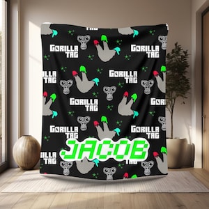 May include: Black and green tapestry with a repeating pattern of a grey alien with green and red fingers. The text "GORILLA TAG" is repeated throughout the tapestry. The name "JACOB" is written in large green letters in the center of the tapestry.