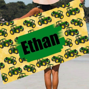 May include: A yellow beach towel with a green and black tractor pattern. The name "Ethan" is written in black letters on a green background.