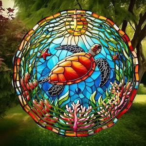 Puede incluir: Un atrapasol de vidrio emplomado con una colorida tortuga marina nadando en un océano azul con coral y algas marinas. El atrapasol es redondo y tiene un borde dorado.