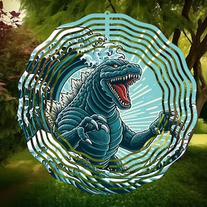 Puede incluir: Un molinillo de viento de metal con un diseño de Godzilla azul y verde. El molinillo tiene una forma circular con múltiples capas de metal que giran con el viento. El diseño presenta a Godzilla emergiendo de una ola.