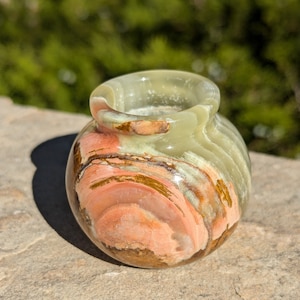 Könnte beinhalten: Eine kleine, runde Onyx-Vase in Grün, Braun und Rosa mit einer glatten, polierten Oberfläche.