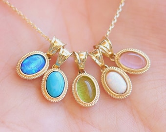 Puede incluir: Un collar de cadena de oro con cinco colgantes de forma ovalada, cada uno con una gema diferente: ópalo, turquesa, verde, blanco y cuarzo rosa.