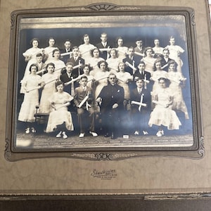 Puede incluir: Fotografía en blanco y negro de un grupo de personas, probablemente una clase u organización, posando formalmente. La imagen está enmarcada e incluye el nombre del estudio, "Stankunas Studio, 295 S. Halsted St. Chicago."