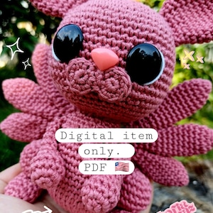 Könnte beinhalten: Ein gehäkeltes rosa Kaninchen mit großen schwarzen Augen und einer rosa Nase. Das Kaninchen hat Flügel und sitzt auf einer Hand. Der Text "Digital item only. PDF" ist auf dem Bild zu sehen.