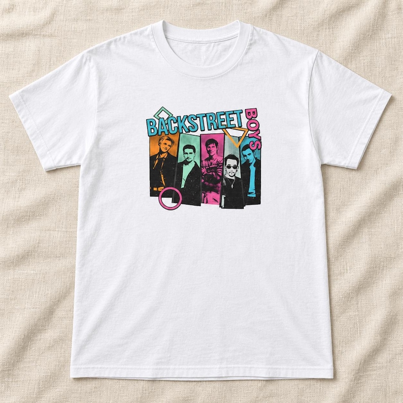 May include: A white short-sleeve t-shirt featuring a graphic print of the Backstreet Boys. The design includes five individual portraits of the band members in colorful rectangular frames, with the text BACKSTREET BOYS and geometric shapes.