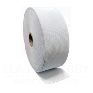 May include: A roll of white elastic band material. The elastic is tightly woven and appears to be made of a durable fabric. The roll is partially unraveled, showing the flat, flexible nature of the material. The background is white.