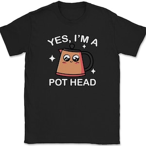 May include: Black t-shirt with the text "YES, I'M A POT HEAD" and a cartoon coffee pot graphic. The coffee pot is brown with a pink outline and a smiling face. White stars are on either side of the graphic.