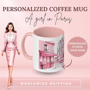 Peut inclure: Une tasse à café rose avec un motif blanc représentant une scène de rue parisienne. La tasse a une anse rose et un bord rose. Le motif représente un bâtiment rose avec un auvent rose et une femme qui marche dans la rue. Le texte "A girl in Paris" est écrit en cursive au-dessus de la tasse.