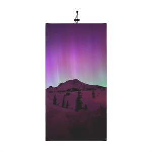 Peut inclure: Un sommet de montagne avec une légère couche de neige se détache sur un ciel d'aurore boréale violet et vert vibrant.
