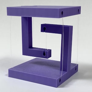 May include: A purple, geometric sculpture with a seemingly impossible design. The structure consists of a base, a top, and a central element, all connected by clear strings. The sculpture is a vibrant shade of purple and appears to defy gravity.