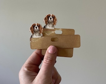 May include: Two brown and white Cavalier King Charles Spaniel dog stickers on a brown cardboard tag with a hole in the top.