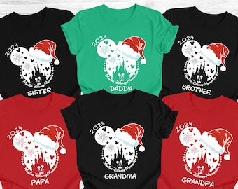 May include: Set of 6 t-shirts featuring a white Mickey Mouse silhouette with a red Santa hat, fireworks, and Cinderella's castle. The shirts are red, black, green, and blue with the text "2024 Making Disney Memories" and "Sister", "Daddy", "Brother", "Papa", "Grandma", and "Grandpa" printed on each shirt.