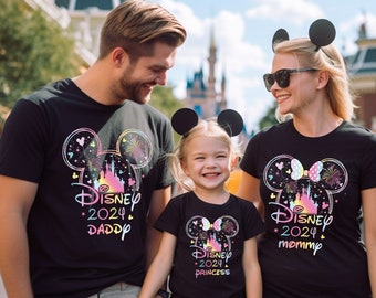 May include: A family of three wearing matching black t-shirts with a colorful Disney castle graphic and the text "Disney 2024" with the words "Daddy", "Mommy", and "Princess" underneath.