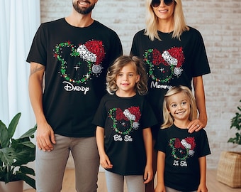 May include: A family of four wearing black t-shirts with a Christmas Mickey Mouse design. The shirts say "Daddy", "Mommy", "Big Sis", and "Lil Sis".