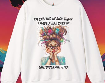May include: A white long-sleeve sweatshirt featuring a graphic of a person with messy hair styled with various colorful art supplies. The text reads, I'M CALLING IN SICK TODAY, I HAVE A BAD CASE OF DONTGIVEASHIT-ITIS, printed in black lettering.