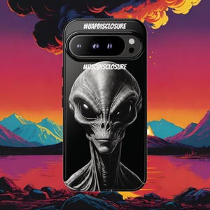 May include: Black smartphone case featuring a detailed gray alien portrait. The case has the text "#UAPDISCLOSURE" and "#USODISCLOSURE" printed on it. The background shows a colorful landscape with mountains, a lake, and a sunset.