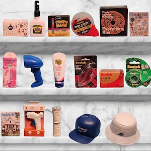 May include: A collection of miniature items, including a bottle of glue, a roll of tape, a pack of Post-it notes, a roll of tape dispenser, a box of cards, a book, a bottle of lotion, a barcode scanner, a roll of tape, a roll of film, a glue gun, a lipstick, a baseball cap, and a bucket hat.