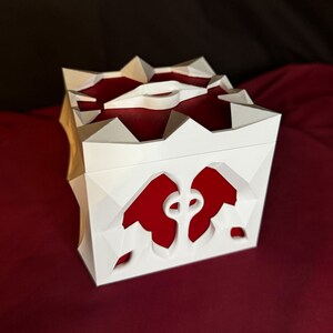 May include: A white 3D printed box with a red interior. The box has a geometric design with a heart-shaped cutout on the front.