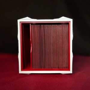 May include: White box with a red interior, designed to hold and organize cards. The box has a divider in the middle, creating two separate compartments.