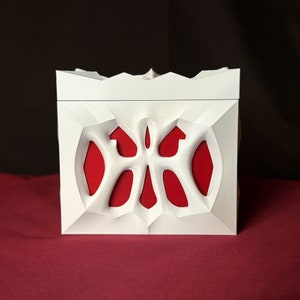 May include: White box with a red interior and a decorative, intricate, white design on the front.